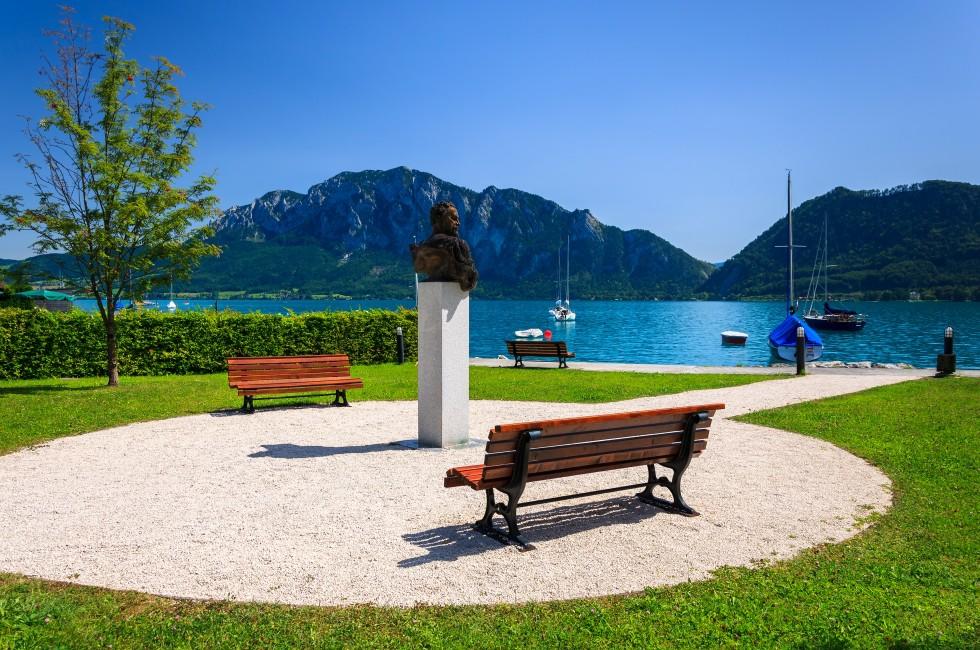 Benches with statue of a man in waterfront area of Attersee lake on summer sunny day, Austria