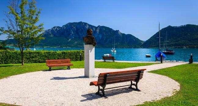 Benches with statue of a man in waterfront area of Attersee lake on summer sunny day, Austria